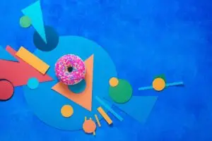 Pink glazed donut on a colorful background with geometric shapes Color block food flat lay with copy space Brand You Creative Brand You Creative Best Branding Agency America